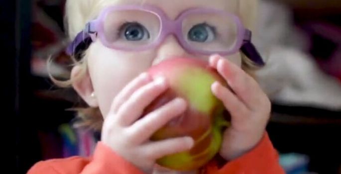 Little girl with glasses eating an apple
