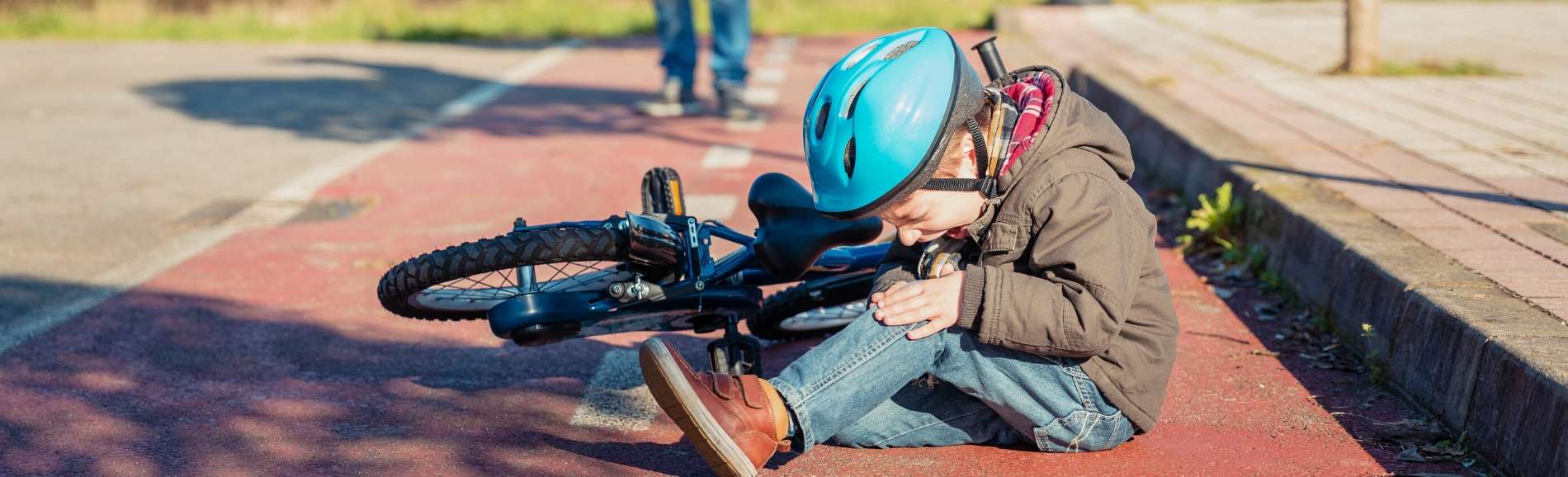 Young boy wearing helmet who's fallen off his bike